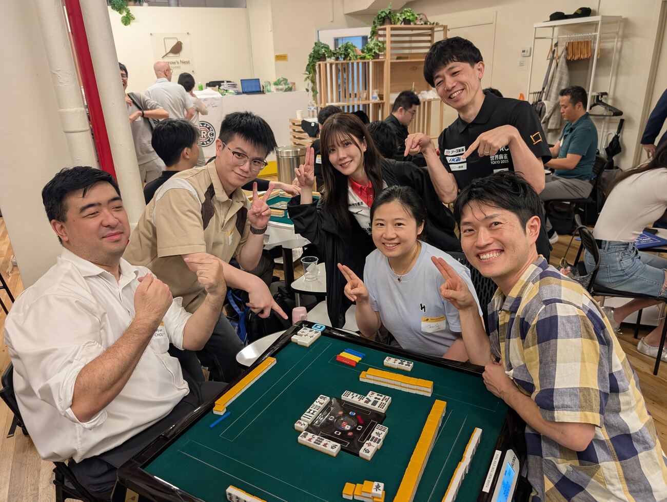 A table of smiling players flashing peace signs mid-game